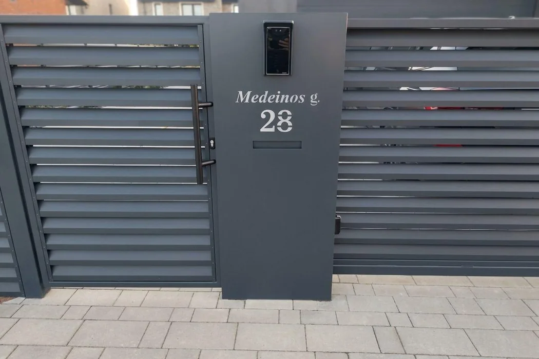 Metalinė pašto konsolė su namo numeriu prie vartų